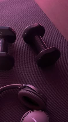 headphones and dumbbells on the floor in front of a pair of purple dumbbells