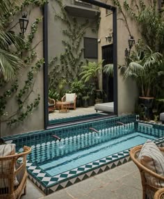 an indoor swimming pool surrounded by greenery and wicker chairs with mirrors on the wall