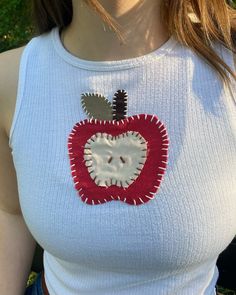 a woman wearing a white top with an apple applique on it