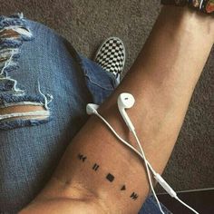 a person with a tattoo on their arm has ear buds attached to the wrist and is holding an mp3 player