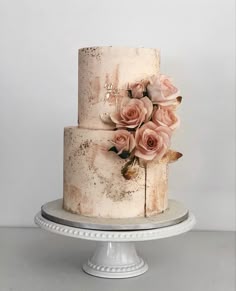 a three tiered cake with pink flowers on top and frosting around the edges