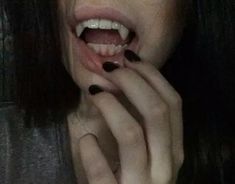 a woman with black nail polish holding her hand up to her mouth