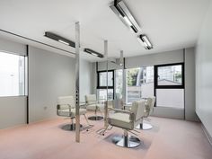 an empty room with chairs, tables and windows in the middle is shown at one end