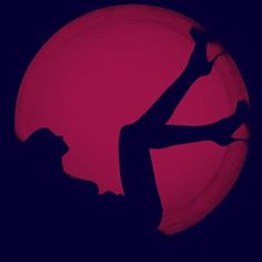the silhouette of a woman is shown in front of a red ball with her arms up