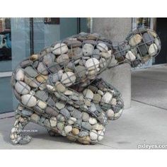 there is a sculpture made out of rocks on the sidewalk with words written below it
