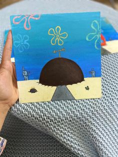 a person holding up a small piece of art