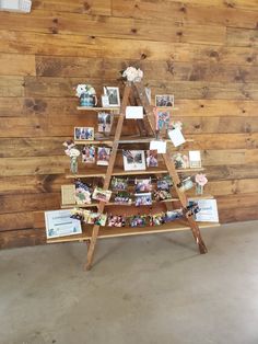 a wooden christmas tree with pictures and cards on the top, in front of a wood wall