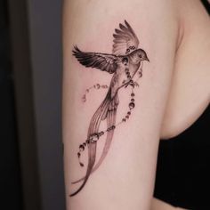 a woman's arm with a bird and beads tattoo on the left side of her arm