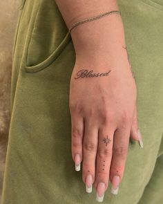 a woman's hand with a small tattoo on her left wrist and the word balanced written in cursive writing