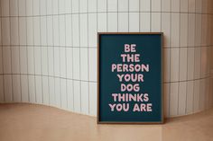 a sign that says be the person your dog thinks you are in front of a tiled wall