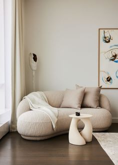 a living room filled with furniture next to a large white painting on the wall and wooden floor