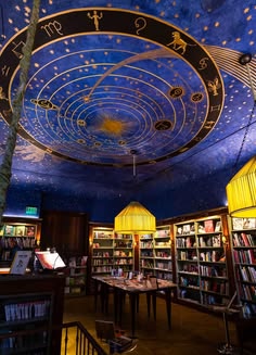 a library filled with lots of books under a blue ceiling covered in stars and zodiac symbols