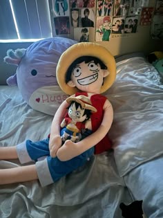 a doll sitting on top of a bed next to a stuffed animal