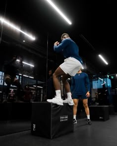 a man is jumping in the air on top of a black box while people watch