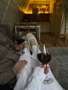 two people sitting on a couch holding wine glasses