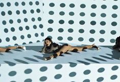 two women are laying on the floor in front of a wall with circles and dots