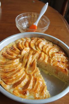 a pie sitting on top of a wooden table next to a bowl with a slice cut out