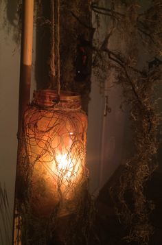 a candle is lit in a jar with vines on the outside and inside, next to a door
