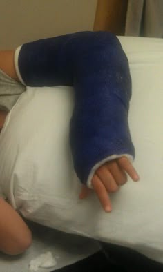 a doll with a cast on it's arm laying next to a pillow