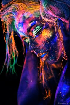 a woman with her face painted in neon colors and hair is posing for the camera
