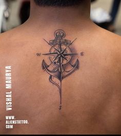 the back of a man's neck with an anchor and compass tattoo on it