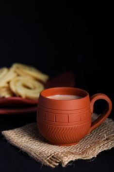 a cup of coffee sitting on top of a table next to some crackers and a plate
