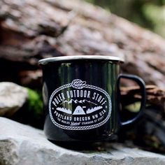 a black coffee mug sitting on top of a rock