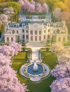 an aerial view of a large white mansion surrounded by trees with pink flowers in bloom