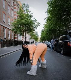 a woman with long black hair is bent over on the street