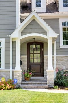 a house with a brown front door and white trim on the windows, along with flowers