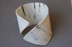 a white vase sitting on top of a gray table next to a black and white object