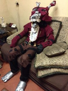 a man dressed as a demon sitting on top of a couch