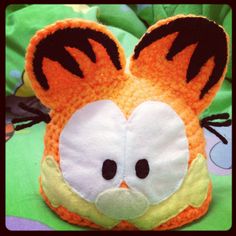 a close up of a stuffed animal on a green blanket with black eyes and ears