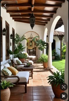 an outdoor covered patio with seating and potted plants on either side of the porch