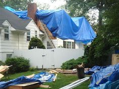the back yard is covered with blue tarps and plastic sheeting as it sits in front of a house