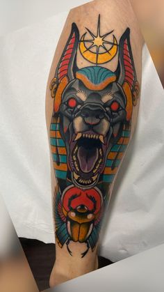 an egyptian tattoo on the leg of a man's arm, showing his teeth and head