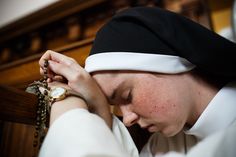 a woman wearing a black and white hat holding a rosary