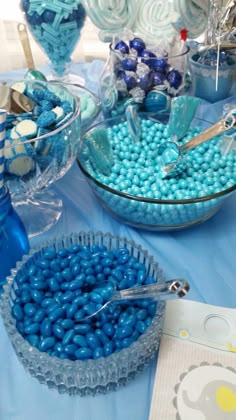 blue candies are in bowls on a table with other candy items and desserts