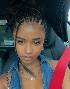 a woman sitting in the back seat of a car wearing a blue shirt and red belt