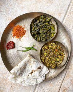 three bowls filled with different types of food on top of a metal plate next to another bowl