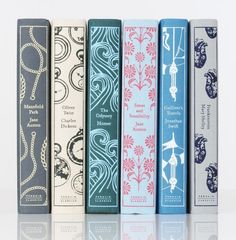 four books are lined up next to each other on a white surface, one is blue and the other is pink