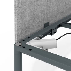 an electronic device is attached to the side of a metal frame with a white wall plugged into it