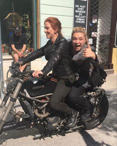 two women sitting on a motorcycle giving thumbs up