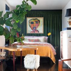 a bed room with a neatly made bed next to a green curtain and a painting on the wall