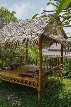 a bamboo bed with a thatched roof in the middle of some grass and trees