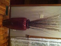 there is a tall vase with grass in it on the floor next to a door