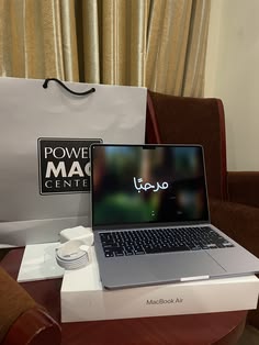 an open laptop computer sitting on top of a white box next to a brown chair