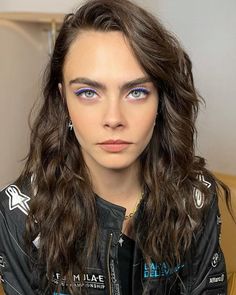 a woman with long hair and blue eyes wearing a black leather jacket is looking at the camera