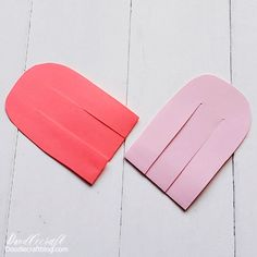 two pieces of pink paper cut out to look like an oven mitt on a white wood floor