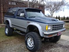 the truck is parked on the side of the road in front of a brick building